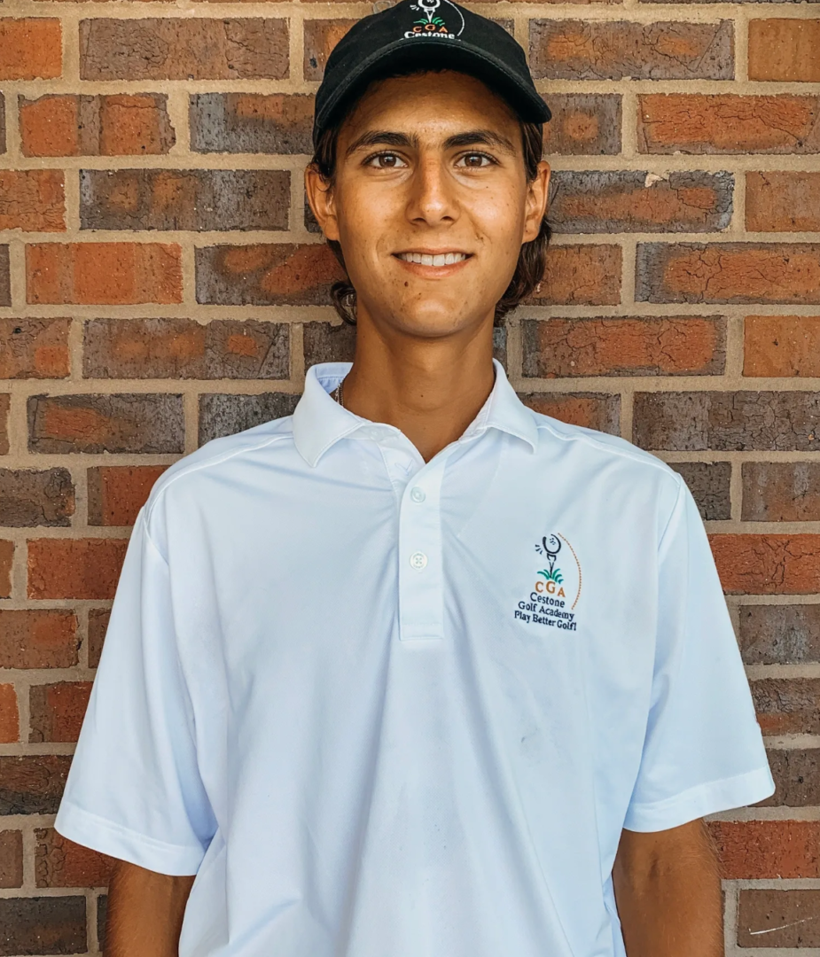 A man in white shirt and hat standing next to brick wall.