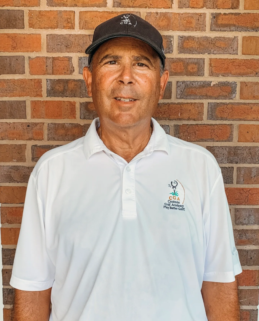 A man in white shirt and hat standing next to brick wall.