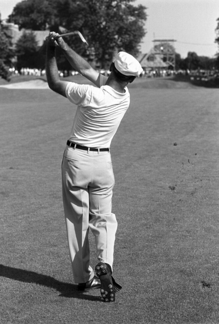 A man in white pants and a hat is playing golf.