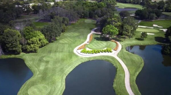 A golf course with trees and water in the background.